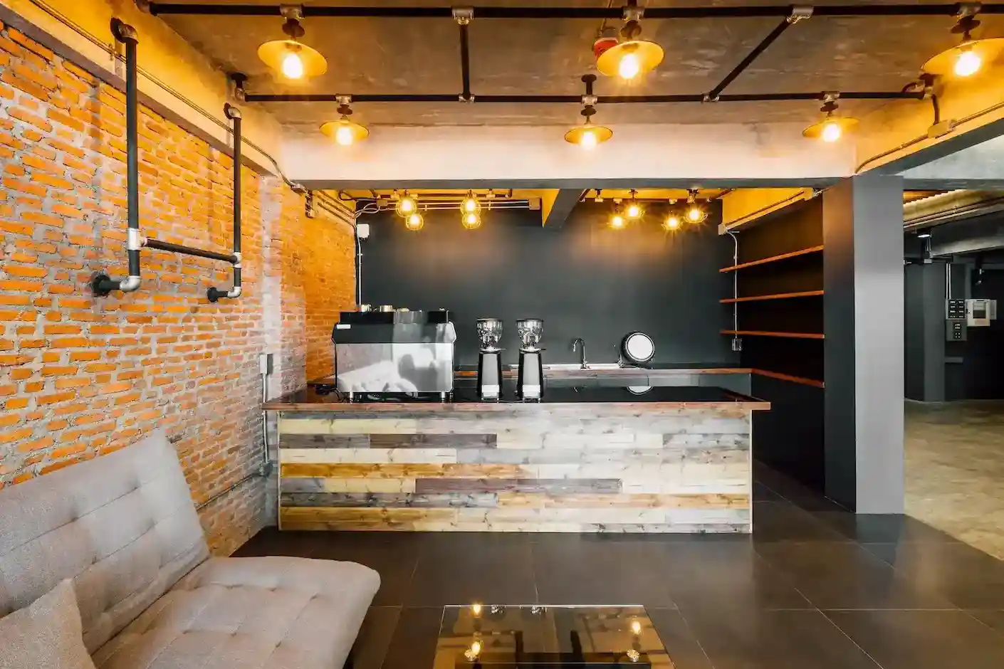 Amplia oficina de espacio abierto con diseño minimalista y moderno, equipada con escritorios individuales de madera clara, sillas de oficina ergonómicas, monitores de computadora, y una iluminación fluorescente lineal en el techo que asegura un ambiente de trabajo luminoso y funcional.
